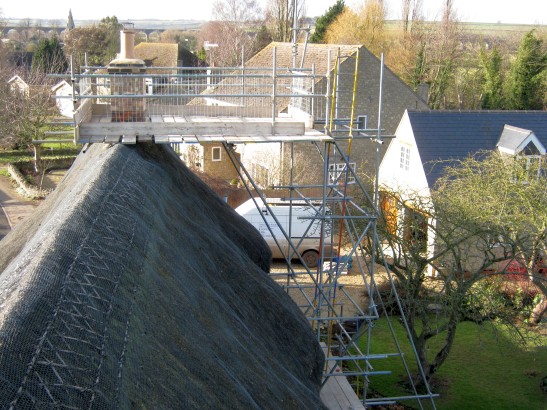 Scaffolding erected over thatched roof prior to chimney being raised and re-lined