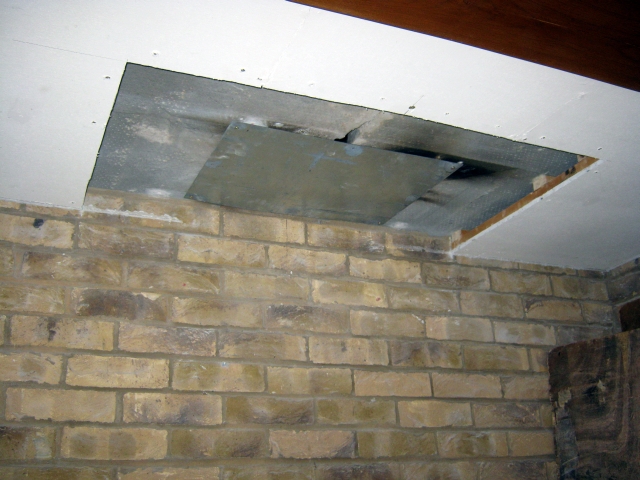 Unsafe wooden battens near flue cut back to safe distance during installation of stove